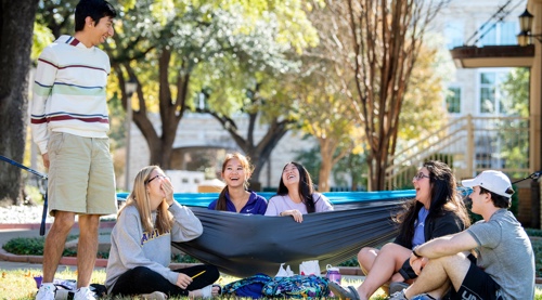 Six students sitting around in a group laughing.